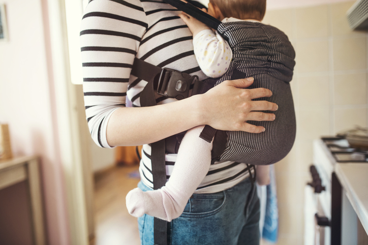 Young mother having her cute little daughter in baby carrier
